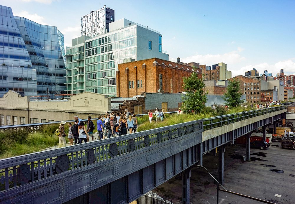 Visitors walking the elevated High Line park in Manhattan, with the IAC Building in the background