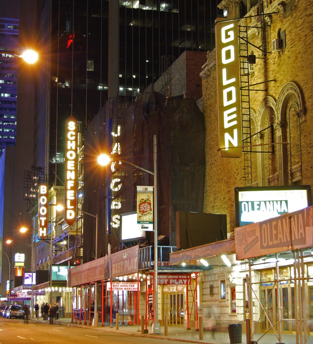 Illuminated Broadway theater marquees on 45th Street in the Theater District at night